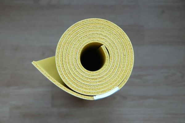 A neatly rolled yoga mat on a wooden floor.